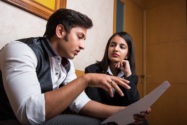Indiase jonge zakenmensen of advocaten die overleggen of discussiëren terwijl ze papier of documenten in de hand houden