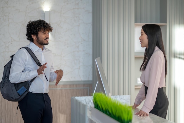 Indiase jongeman met rugzak in gesprek met een meisje bij de receptie