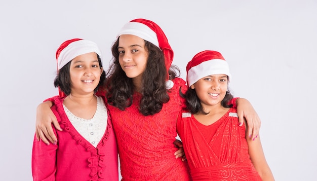 Indiase kinderen vieren Kerstmis met geschenken, boom en rode kerstman hoed, geïsoleerd op witte achtergrond