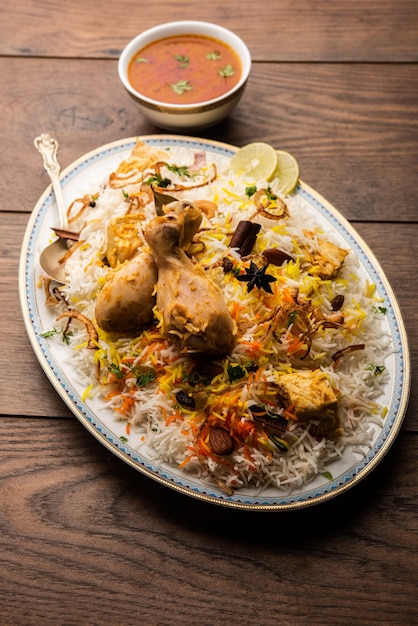 Indiase Kip Biryani geserveerd in een terracotta kom met yoghurt op witte achtergrond. selectieve focus