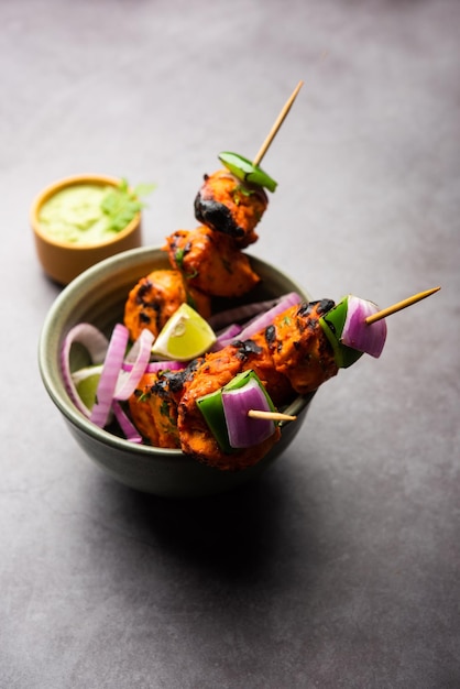 Indiase kip tikka kebab, gemarineerd in kruiden en yoghurt en geroosterd in tandoor. geserveerd met groene chutney en ui. selectieve focus