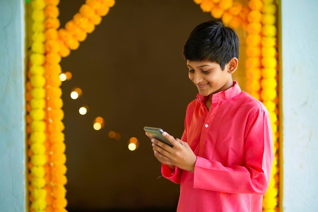 Indiase kleine jongens die smartphone gebruiken en genieten van diwali-festival.