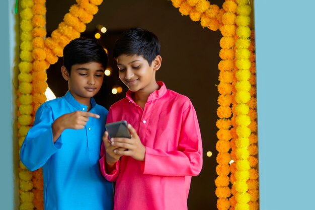 Indiase kleine jongens die smartphone gebruiken en genieten van diwali-festival.