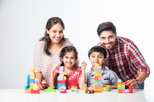 Indiase kleine kinderen die kleurrijk blokspeelgoed spelen met jonge ouders, tegen een witte achtergrond