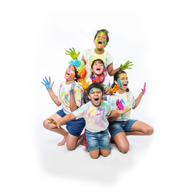 Indiase kleine kinderen of vrienden of broers en zussen die Holi-festival vieren met gulal of poederkleur, snoep, pichkari of spray, geïsoleerd op witte achtergrond