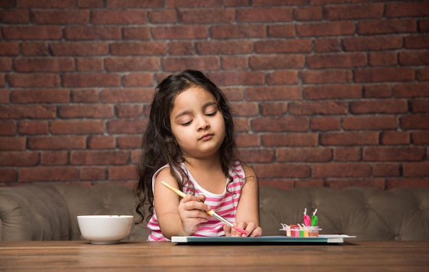 Indiase kleine meid tekenen of schilderen met kleuren over papier, selectieve focus