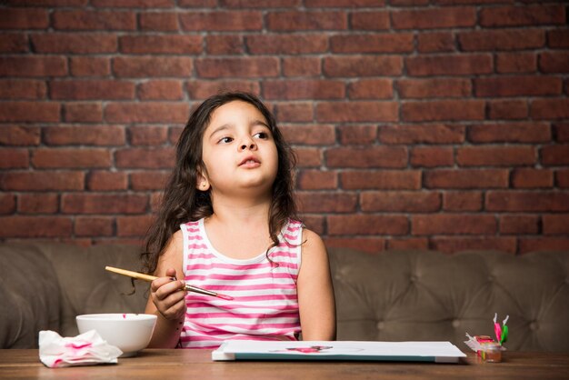 Indiase kleine meid tekenen of schilderen met kleuren over papier, selectieve focus