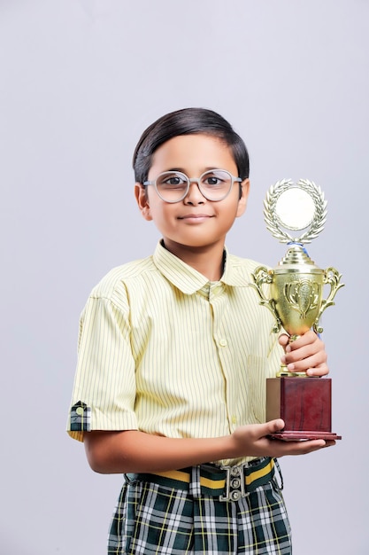 Indiase kleine schooljongen die uitdrukking geeft met trofee