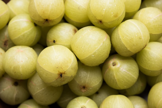 Indiase kruisbes of Amla (Phyllanthus emblica) in een rieten mand over kleurrijk of houten oppervlak, selectieve focus