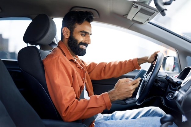 Indiase man die met zijn smartphone berichten stuurt terwijl hij een auto rijdt