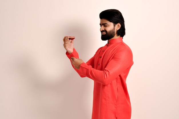 Indiase man draagt Orange Kurta Holding en kijkt naar Diya voor Diwali