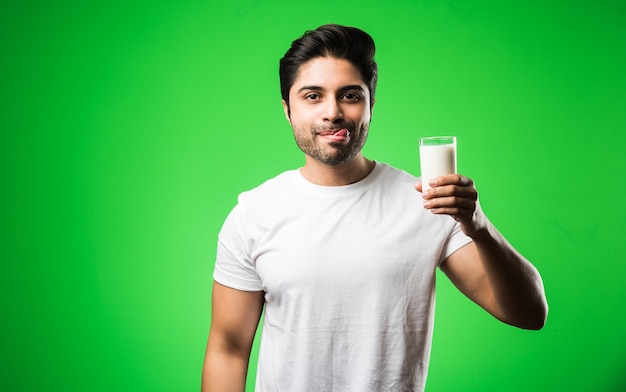 Indiase man drinkt melk in glas terwijl hij geïsoleerd staat