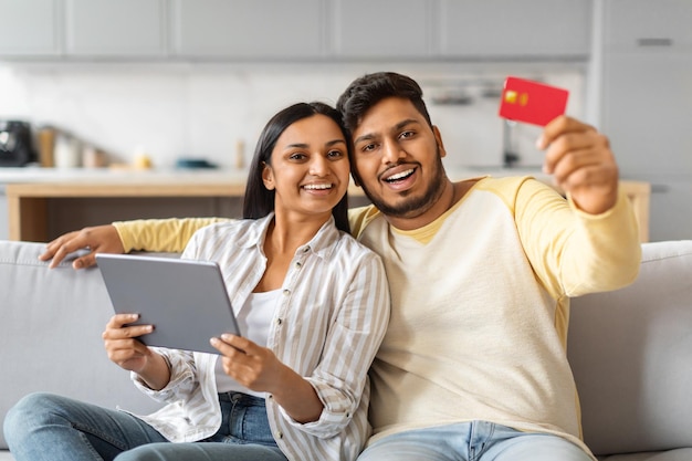 Indiase man en vrouw met tablet en creditcard op de bank