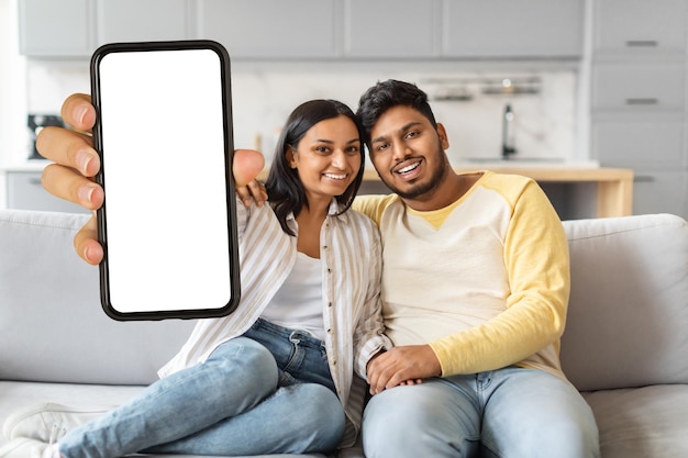 Indiase man en vrouw zitten op de bank met een lege mobiele telefoon.