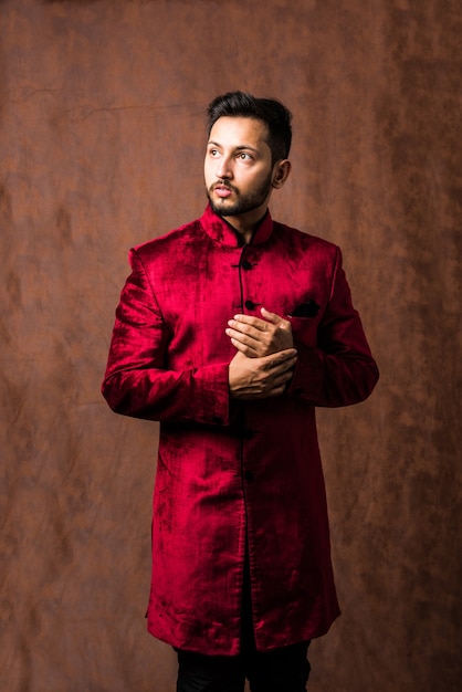 Indiase man in traditionele kleding OF kurta, pyjamadoeken. Mannelijke mannequin in sherwani, poseren of staan tegen bruine grunge achtergrond, selectieve focus