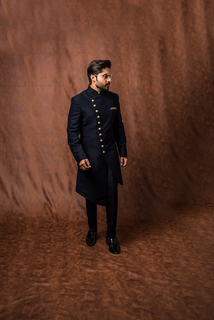 Indiase man in traditionele kleding OF kurta, pyjamadoeken. Mannelijke mannequin in sherwani, poseren of staan tegen bruine grunge achtergrond, selectieve focus