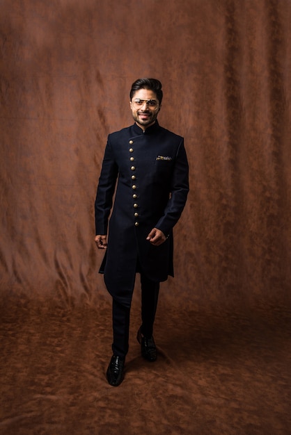 Indiase man in traditionele kleding OF kurta, pyjamadoeken. Mannelijke mannequin in sherwani, poseren of staan tegen bruine grunge achtergrond, selectieve focus