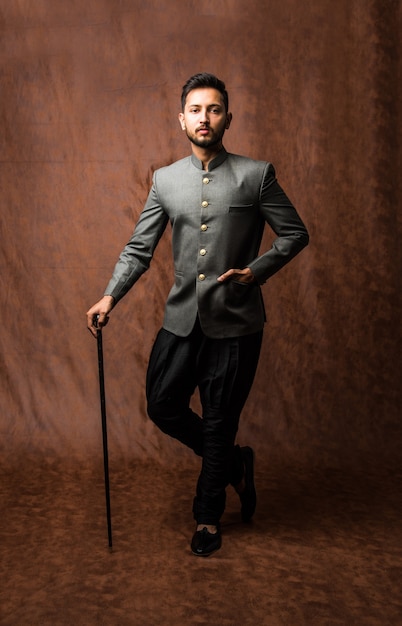 Indiase man in traditionele kleding OF kurta, pyjamadoeken. Mannelijke mannequin in sherwani, poseren of staan tegen bruine grunge achtergrond, selectieve focus