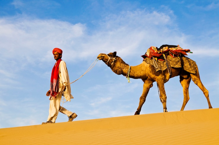 Foto indiase man loopt door de woestijn met zijn kameel