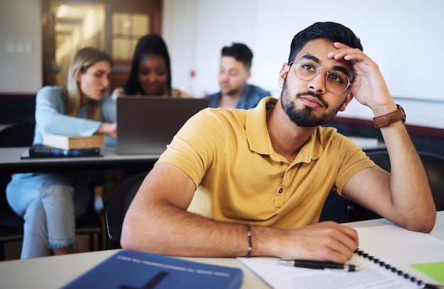 Indiase man student en verveeld in de klas moe en stress met aantekeningen onderzoek of taak Jonge mannelijke man of uitgeput voor onderwijstest of aantekeningen voor opdracht met hoofdpijn en depressief