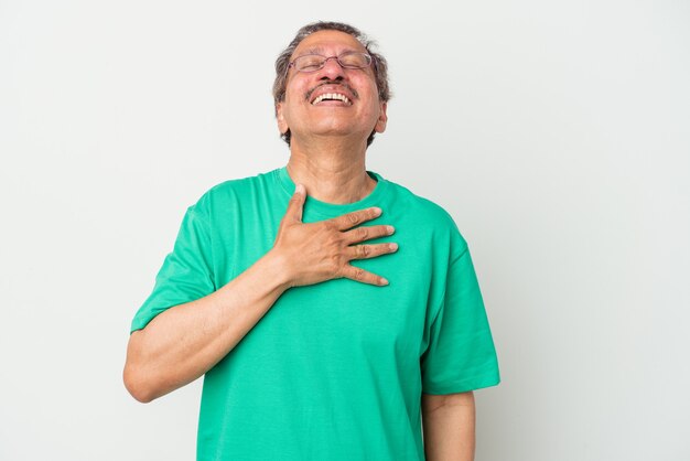 Indiase man van middelbare leeftijd geïsoleerd op een witte achtergrond lacht hardop met de hand op de borst.