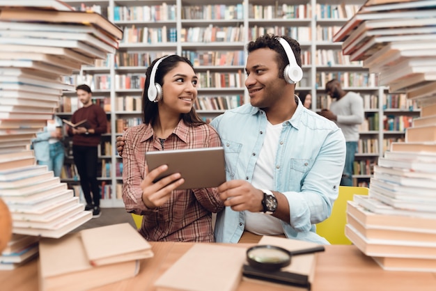 Indiase meisje en jongen omringd door boeken in de bibliotheek.