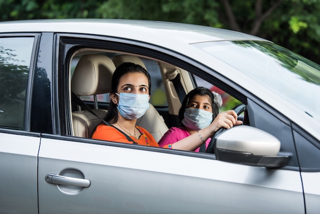 Indiase moederdochter met gezichtsmasker of medisch masker tijdens het autorijden
