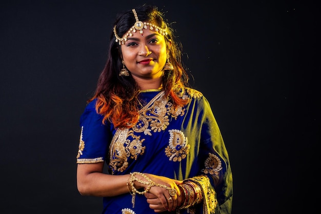 Indiase mooie mode brunette vrouw in blauwe traditionele bruiloft rijke sari met make-up op zwarte studio achtergrond.