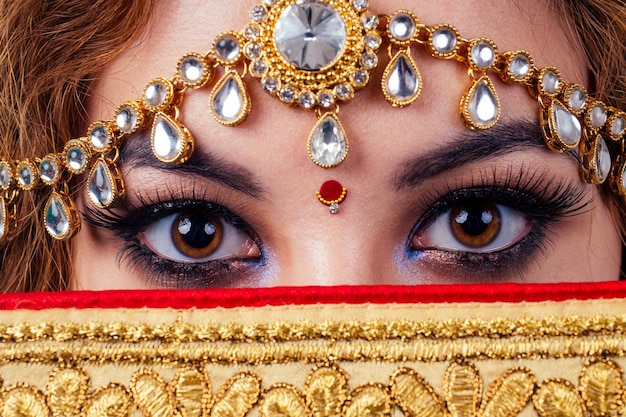 Indiase mooie mode brunette vrouw in groene traditionele bruiloft rijke sari met gouden sieraden neus ring piercing nath professionele make-up op witte studio achtergrond bindi close-up