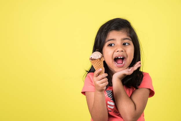 Indiase of Aziatische schattige kleine kinderen die ijs of mangoreep of snoep eten. Geïsoleerd over kleurrijke achtergrond