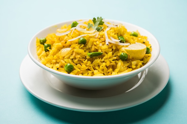 Indiase ontbijtschotel poha ook bekend als pohe of aalu poha bestaande uit geklopte rijst of afgeplatte rijst. de rijstvlokken zijn licht gebakken in olie met kruiden geserveerd met hete thee