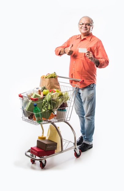 Indiase oude man met winkelwagen of trolley vol groenten, fruit en boodschappen