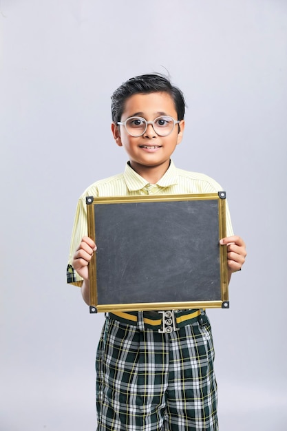 Indiase schooljongen die een zwart bord met kopieerruimte toont