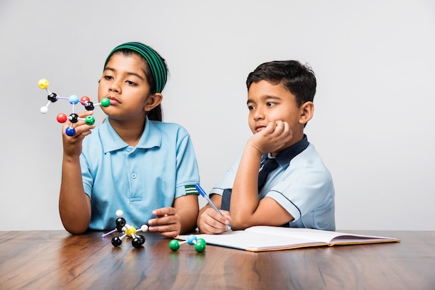 Indiase schooljongen en -meisje of wetenschapsstudent in uniform Molecular Model Kit gebruiken voor het bestuderen van natuurkunde, selectieve focus