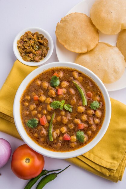 Indiase schotel pittige kikkererwten curry ook bekend als Chola of Chana Masala of algemeen Chole, geserveerd met gebakken puri of poori over kleurrijke of houten achtergrond. Selectieve focus