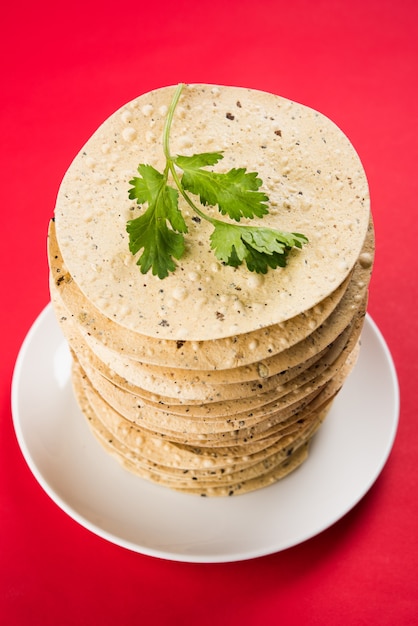 Indiase snacks, stapel gefrituurde of geroosterde Mung Urad dal-crackers of papad, een bijgerecht bij lunch en diner. Geserveerd in een rieten mand of bord met korianderblad.