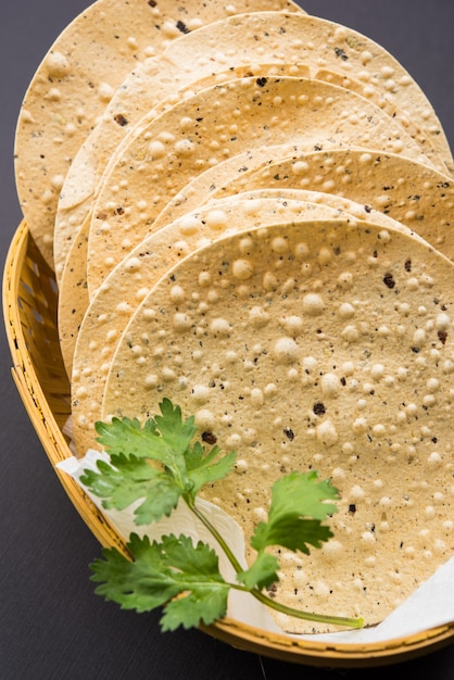 Indiase snacks, stapel gefrituurde of geroosterde Mung Urad dal-crackers of papad, een bijgerecht bij lunch en diner. Geserveerd in een rieten mand of bord met korianderblad.