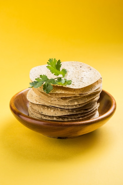 Indiase snacks, stapel gefrituurde of geroosterde Mung Urad dal-crackers of papad, een bijgerecht bij lunch en diner. Geserveerd in een rieten mand of bord met korianderblad.