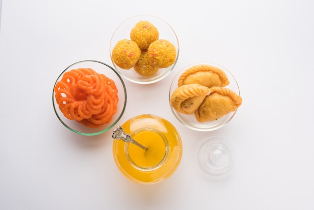 Indiase snoepjes Gujiya, motichoor laddu en jalebi en geklaarde boter of Indiase desi ghee in een pot, selectieve focus