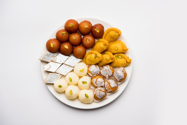 Indiase snoepjes in een bord bevatten Gulab Jamun, Rasgulla, kaju katli, morichoor of Bundi Laddu, Gujiya of Karanji voor diwali-viering