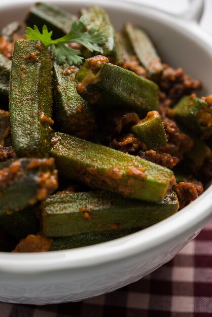 Indiase stijl Masala Sabji OF Sabzi van gebakken Bhindi OF Okra, ook bekend als Ladyfinger, geserveerd in een kom op een humeurige achtergrond. selectieve focus