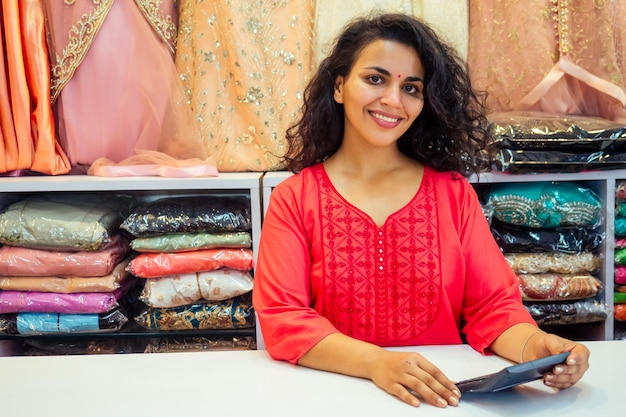 Indiase verkopersvrouwen in rode kurta staan in haar studioshowroom