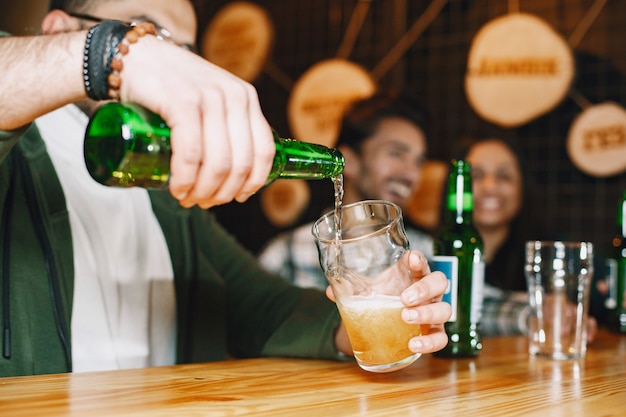 Indiase vrienden in een pub. Jongens en meisje aan de bar. Viering boven een mok bier.