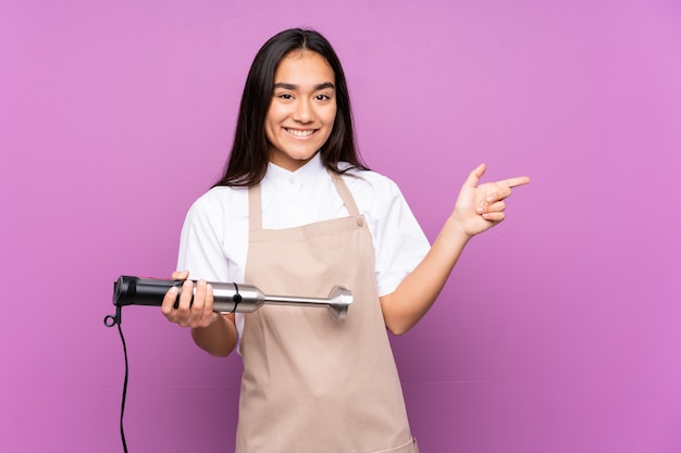 Indiase vrouw met behulp van handmixer op paarse wijzende vinger aan de zijkant