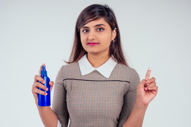 Indiase vrouw met fles zonnebrandcrème in studio witte achtergrond.