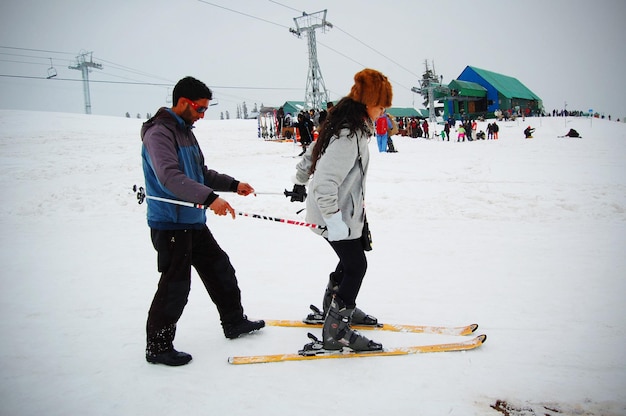 Indiase vrouw met skileraar die studeert om te skiën op de helling in Gulmarg, Jammu en Kasjmir, India