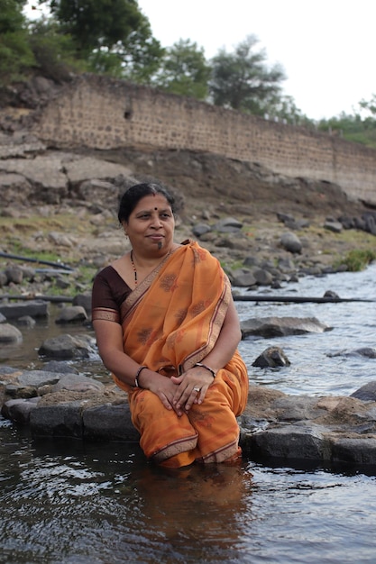 Indiase vrouwen zitten in de buurt van de rivier, Indiase vrouwen in saree zitten aan de rivier en kijken naar de zonsondergang