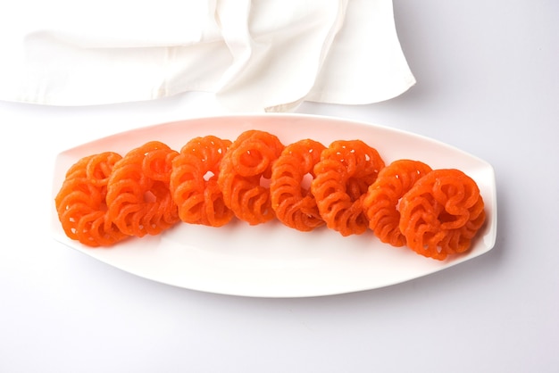 Indiase zoete Imarti of Jalebi geserveerd in witte keramische plaat op witte achtergrond