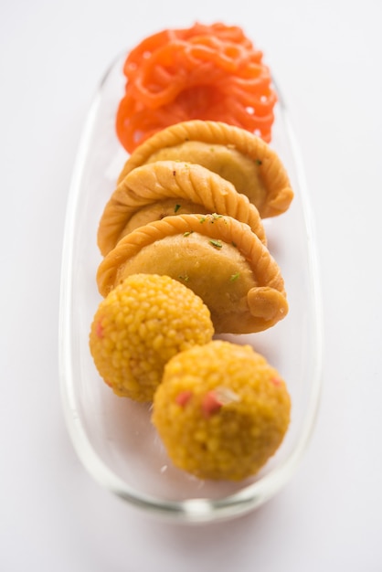 Foto indiase zoete jalebi of imarti, laddu en gujiya geserveerd samen op een witte achtergrond of met geschenken. selectieve focus