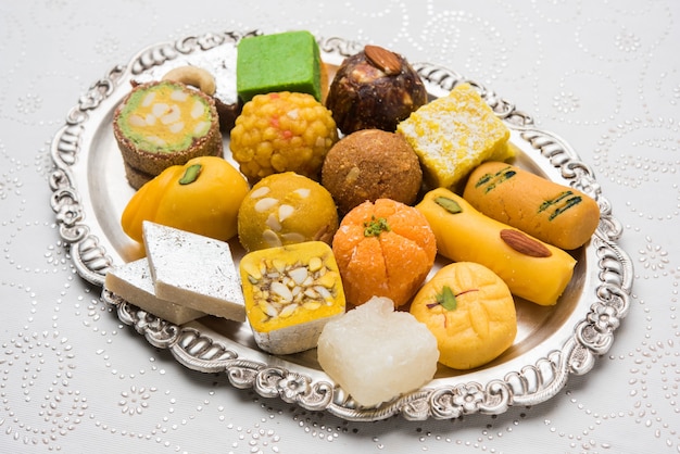 Indiase zoetigheden geserveerd in zilveren of houten bord. verscheidenheid aan Peda, burfi, laddu in decoratieve plaat, selectieve focus